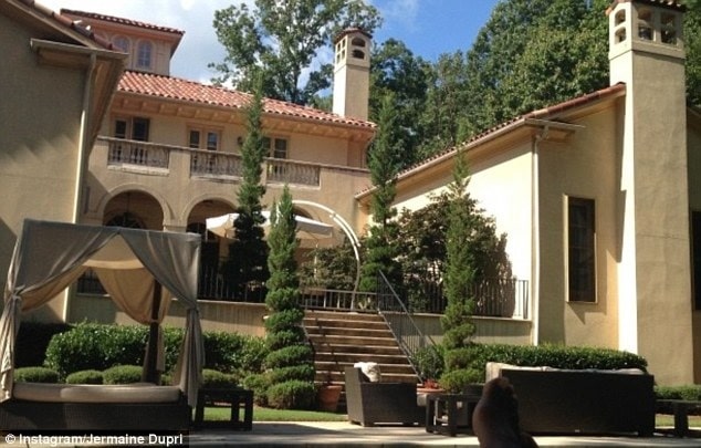 Jermaine Dupri cream-colored house worth $2.5 million with bed and sofa outside with green bushes on the side.
